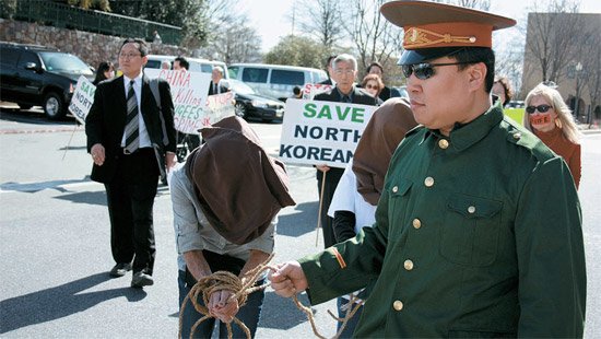 ▲ 2012년 3월 미 인권단체 회원들이 미국 워싱턴 주미 중국대사관 앞에서 탈북자 강제북송에 항의하는 집회를 열었다. 집회 참가자들이 탈북 여성의 얼굴을 가린 채 두 손을 포박해 끌고 가는 중국 공안 모습을 연출하고 있다. ⓒ 연합뉴스