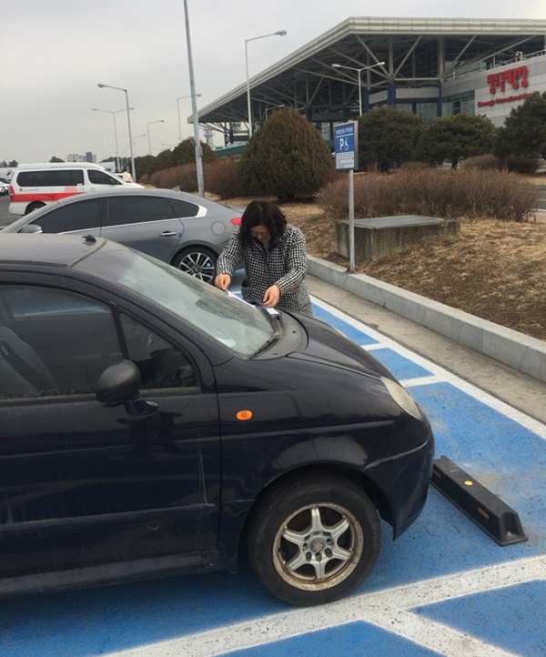 ▲ 청주공항내 장애인 주차구역에 불법 주차한 차량을 담당 공무원이 단속하고 있다.ⓒ충북도