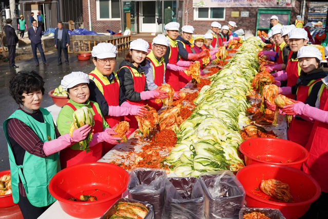 ▲ 농협금융지주 김광수 회장(왼쪽에서 세 번째)과 임직원 봉사단, 자매마을 주민들이 농가에서 직접 재배한 배추, 무 등 우리농산물로 김장김치를 담그고 있다.ⓒ농협금융지주