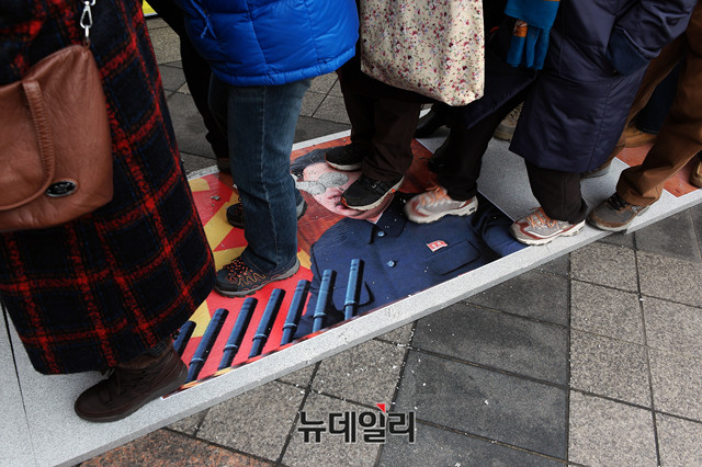 ▲ 지난 2월 24일 우파성향 집회 참석자들이 서울 광화문 동화면세점 앞에서 김정은 사진으로 만든 피켓을 밟고 지나가는 퍼포먼스를 하는 모습. ⓒ뉴데일리 이기륭 기자