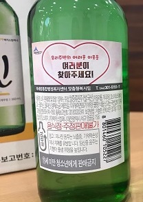 ▲ 세종시 북세종통합행정복지센터와 맥키스컴퍼니가 ‘이제우린’ 소주병에 보조라벨을 부착, 복지사각지대 발굴에 나섰다. 소주 병에 ‘우리 주변의 어려운 이웃을 찾아주세요’ 라벨.ⓒ세종시