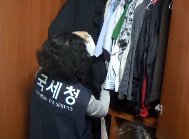 ▲ 국세청 체납전담반 조사관이 체납자의 장롱속 양복에서 은닉한 현금을 추적하고 있다. ⓒ국세청 제공