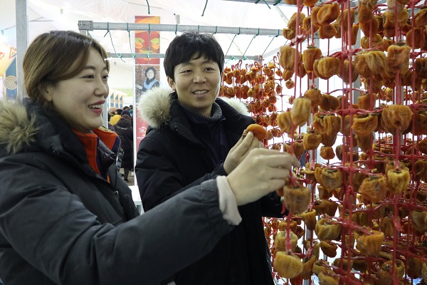 ▲ 감고을 충북 영동에서 지난 14~16일 충북 영동에서 열린 곶감축제에 참여한 관광객들이 주렁주렁 매달린 곶감을 조심스럽게 만저보고 있다. ⓒ영동군