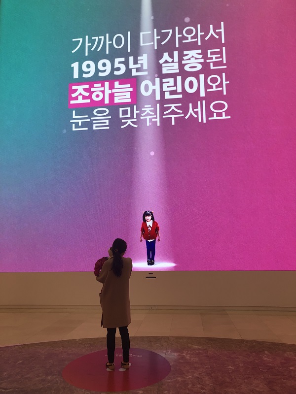 ▲ 스타필드 하남을 방문한 주부 송현숙 씨가 '미디어타워' 앞에서 사진 속 실종 아동과 눈을 마주치고 있다. ⓒ김수경 기자