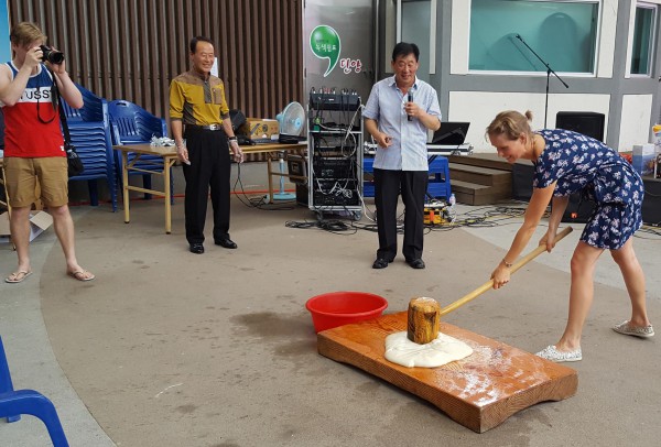 ▲ 충북 단양구경시장을 찾은 외국인 관광객이 떡 메치기를 하고 있다.ⓒ단양군