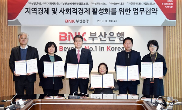 ▲ BNK부산은행은 13일 본점에서 지역 내 사회적 경제기업들과 사회적 경제 및 지역경제 활성화를 위한 업무협약을 체결했다. 사진 왼쪽부터 부산소비자생활협동조합 손동호 상무, (사)에코언니야 박숙경 대표, 부산은행 성동화 경영관리그룹장, (사)한국장애인자립협회 이혜영 대표, ㈜기장사람들 박상호 대표, ㈜블루인더스 박향남 사장. ⓒBNK부산은행