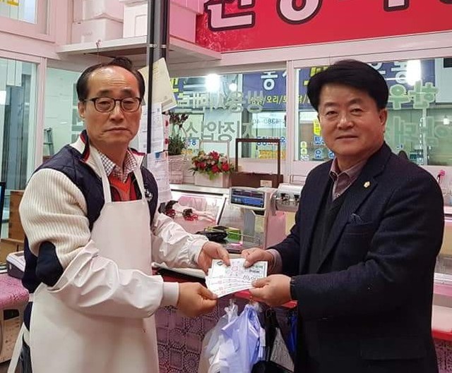 ▲ 배동만 제천시의회(산업건설위)의원(오른쪽)이 제천화폐 모아 챌린지 캠페인에 참여해 고기를 구입하고 사진을 촬영해 자신에 페이스북에 올린 모습.ⓒ배동만 의원 제공