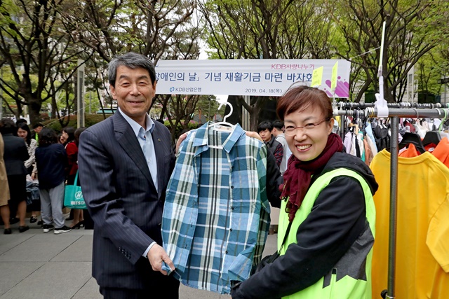 ▲ 이동걸 산업은행장(왼쪽)이 18일 산업은행 앞에서 진행된 '장애인 재활기금 마련을 위한 사랑의 바자회'에 참석해 기증받은 물품을 들어보이고 있다. ⓒ산업은행