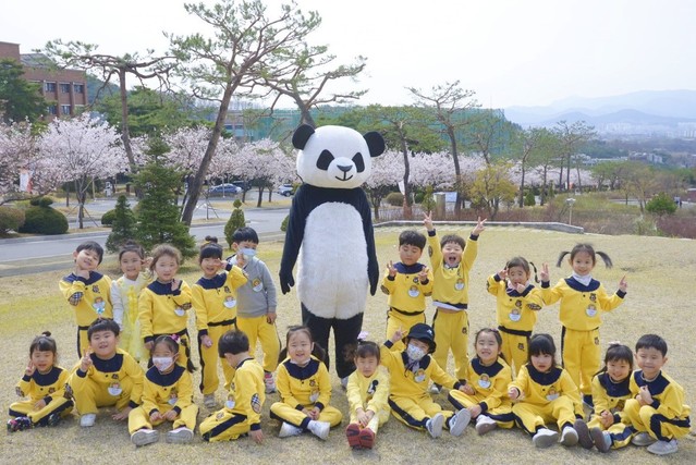 ▲ 18일 세명대 벚꽃놀이 체험행사에 초청된 어린이집 아이들이 캠퍼스 하늘공원 잔디밭에서 기념사진을 찍고 있다.ⓒ세명대학교