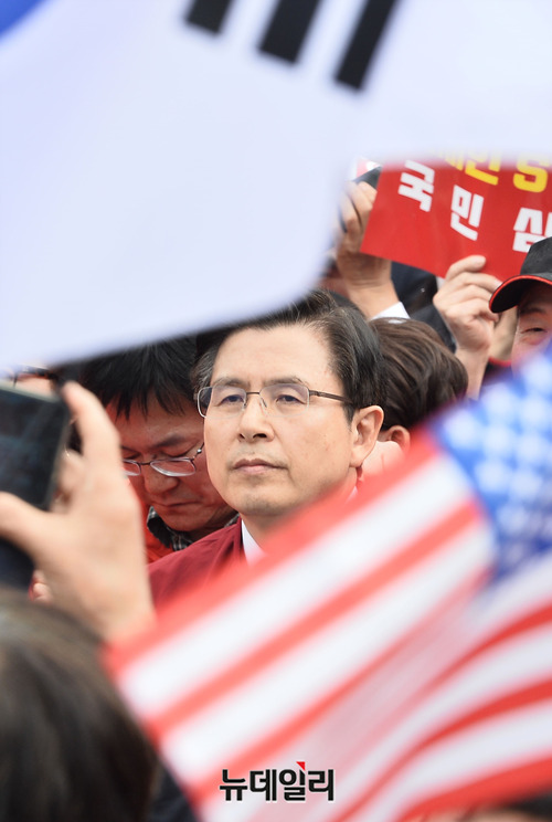 황교안 자유한국당 대표가 20일 서울 광화문 일대에서 열린 한국당 장외투쟁에 참석한 모습. 참가자들이 흔들고 있는 태극기와 성조기 사이로 보이는 황 대표 얼굴.ⓒ박성원 기자