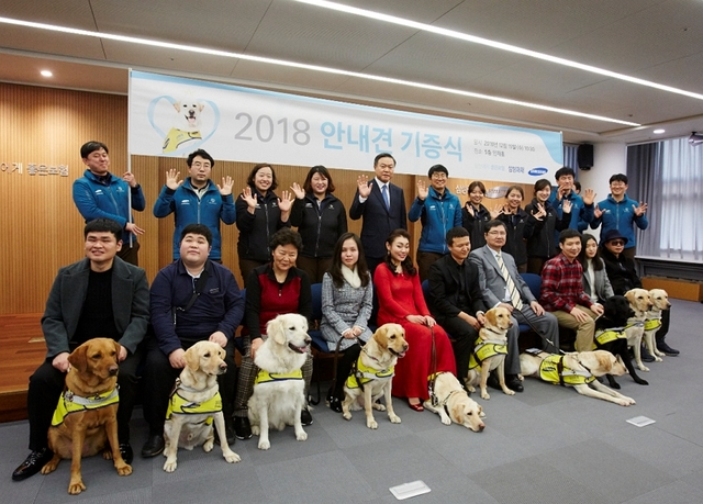 ▲ 삼성화재 안내견 기증식에서 시각장애인과 안내견, 훈련사 등이 단체 촬영을 하고 있는 모습. 뒤쪽 좌측에서 5번째가 최영무 삼성화재 사장.ⓒ삼성화재