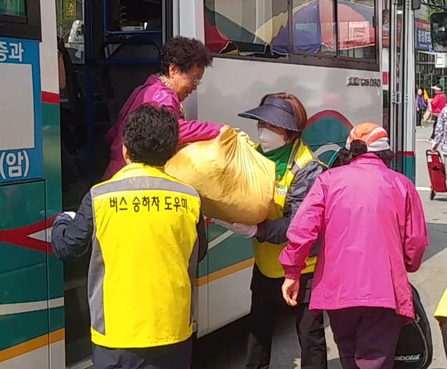 ▲ 지난 6일 버스를 이용해 횡성 5일장을 찾은 할머니의 짐을 들어 내려주고 있는 자원봉사자들 모습.ⓒ횡성군