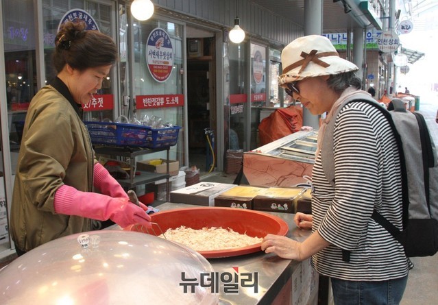 ▲ 광천시장을 찾은 관광객이 새우젓을 사기 위해 상품을 살펴보고 있다.ⓒ목성균 기자