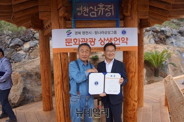 ▲ 제주 탐나라 공화국에서 영천 삼휴정 제막식을 가진뒤 강우현 대표(우)와 최기문 영천시장이 협약서를 들어 보이고 있다. ⓒ김정원 기자