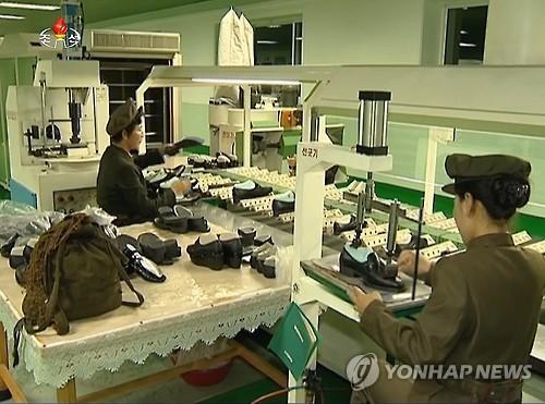 ▲ '전투배낭'을 옆에 두고 군복 차림으로 작업하고 있는 북한의 공장 근로자들ⓒ[사진=연합뉴스]