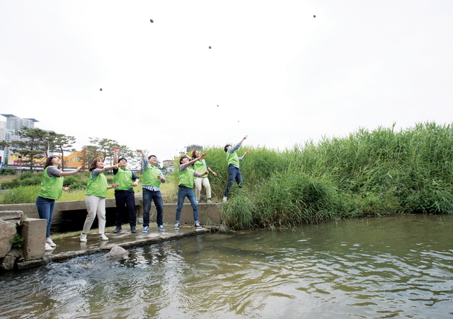 ▲ LS산전봉사단이 3일 충북 청수 무심천에서 친환경 미생물 흙공을 던지는 친환경 캠페인을 진행 중이다. ⓒLS산전
