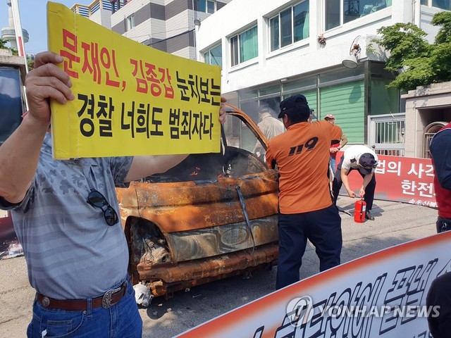 ▲ 사진은 이달 3일 오후 한전 속초지사 앞에서 열린 산불피해 보상을 촉구 집회에서 소방대원이 차량의 불을 끌고 있다. 이 차량은 주최측이 집회장에다가 끌어다 놓은 폐차량이어서 특별한 피해는 없었다. ⓒ연합뉴스