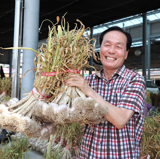 ▲ 김주수 의성군수가 의성마늘을 들이보이고 활짝 웃고 있다.ⓒ의성군