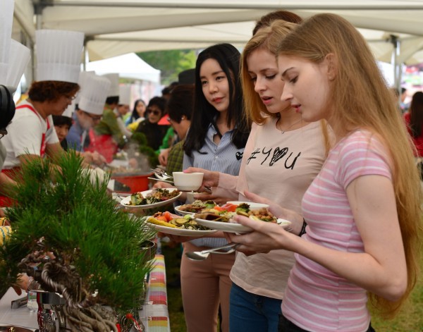 ▲ 지난 한방바이오엑스포 행사 한방음식경연대회에 참가한 업소들의 음식을 맛보기 위해 외국인들이 접시에 음식을 담고 있다.ⓒ제천시