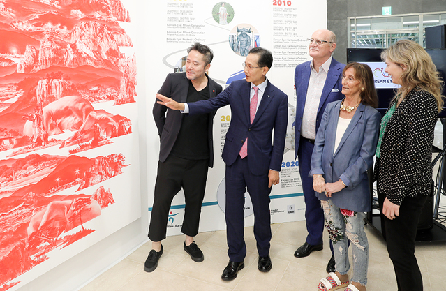 ▲ KEB하나은행이 서울 을지로 소재 본점에서 한국 신진작가들을 위한 글로벌 진출 프로젝트 Korean Eye 2020을 후원하고, ‘Korean Eye 2020 : 한국 동시대 미술’ 전시의 메인 스폰서로 참여한다고 밝혔다. 기념 전시회 시작에 앞서 지성규 KEB하나은행장(왼쪽에서 두번째)이 데이비드 시클리티라(David Ciclitira) PCA 회장 겸 창립자(왼쪽에서 세번째), 세레넬라 시클리티라 (Serenella Ciclitira) PCA CEO 겸 창립자(왼쪽에서 네번째), 필리 아담스(Philly Adams)사치갤러리 총괄디렉터(맨 오른쪽)와 함께 이세현 제1회 코리안아이 작가(맨 왼쪽)로부터 작품에 대한 설명을 듣고 있다.ⓒKEB하나은행