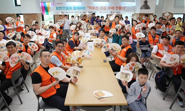 ▲ '어르신 건강 부채 만들기' 봉사활동에 참여한 '호반사랑나눔이'와 그 가족들이 기념촬영을 하고 있다. ⓒ호반