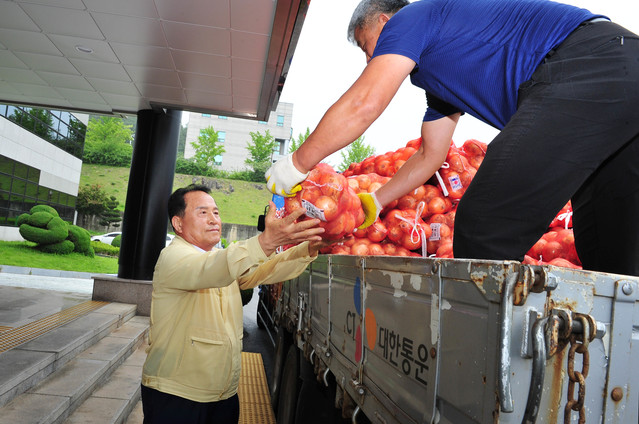 ▲ 김영만 군위군수가 지난 15일 군위군청 주차장에서 개최한 ‘양파 1인 1망 사주기’ 행사에서 양파를 나르고 있다. 이날 김 군수와 공무원 427명이 참여해 양파(10kg) 974망을 구매했다.ⓒ군위군