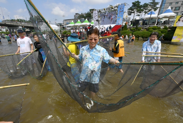 ▲ 이철우 경북도지사가 27일 열린 봉화은어축제에서 은어를 잡고 환하게 웃고 있다.ⓒ경북도