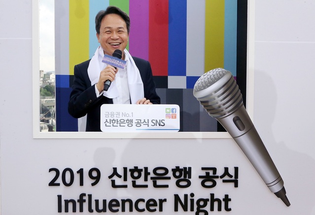 ▲ 29일 서울시 용산구 소월로 소재 복합문화공간 ‘앨리스 몽드’에서 진행된 신한은행 인플루언서 창단식에서 진옥동 은행장이 방송 컨셉 포토월에서 직원들에게 인사하고 있다. ⓒ신한은행