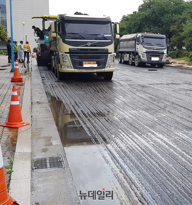 ▲ A건설사가 지난달 28일 오후 3시쯤 장맛비가 내리는 가운데 충북 청주시 청원구 청주문화산업단지 내 진‧출입 도로에 대한 아스콘 포장을 하고 있다.ⓒ김정원 기자