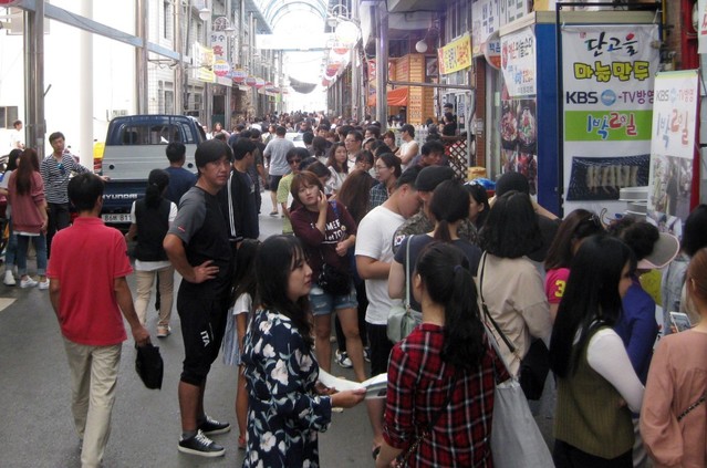 ▲ 단양 구경시장을 찾은 관광객들이 먹거리 골목에서 다양한 단양 맛을 보기 위해 상가 앞에서 기다리고 있는 모습. 구경시장은 여름 휴가철을 맞아 전통시장 콜라보레이션, 야시장 운영 등 다양한 행사를 펼치고 있다.ⓒ단양군