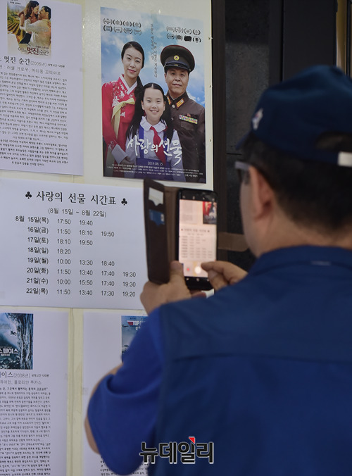 ▲ 영화 '사랑의선물' 상영 시간표를 촬영하는 시민