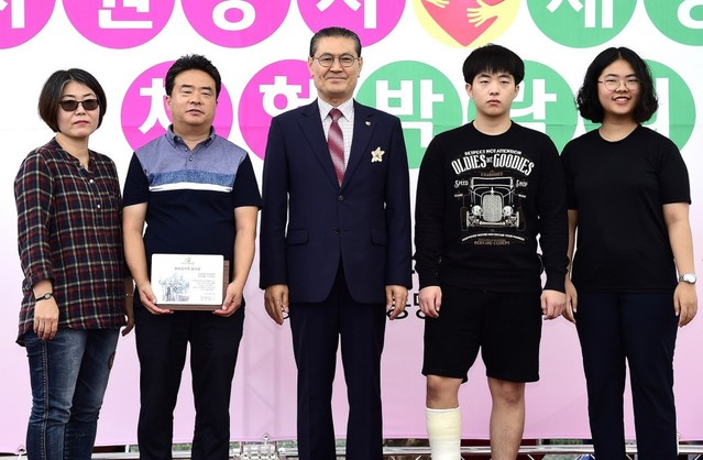 ▲ 지난 31일 제천 여름광장에서 열린 ‘제천자원봉사 재능 나눔 체험박람회’에서 온가족이 자원봉사자로 등록돼 모범사례로 인정 받은 최승태 가족이 정좌현 센터장(가운데)으로부터 '한마음 가족봉사상'을 받고 기념촬영을 하고 있다.ⓒ제천시종합자원봉사센터