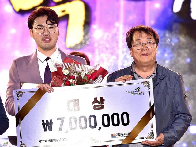 ▲ 지난 19일 제천 여름광장에서 열린 ‘제23회 제천박달가요제’에서 ‘목포행 완행열차’를 불러 대상을 차지한 손동욱(35·경남 김해)씨가 이상천 시장(오른쪽)과 기념촬영을 하고 있다.손동욱씨는 상금 700만원과 가수인증서를 받았다.ⓒ제천시
