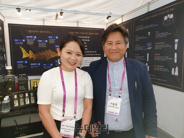 ▲ 2019 오송화장품뷰티엑스포장내 홍보부스를 방문한 싱가폴 바이어와 활짝 웃고 있는 귀농(주)의 이용광 대표(오른쪽).ⓒ박근주 기자