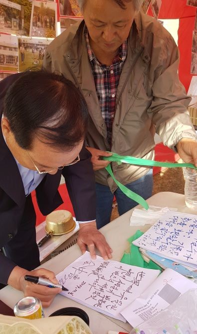 ▲ 김중로 의원이 인추협 고진광 이사장이 바라보고 있는 가운데 방명록에 글을 적고 자신의 사인을 하고 있다.ⓒ인추협