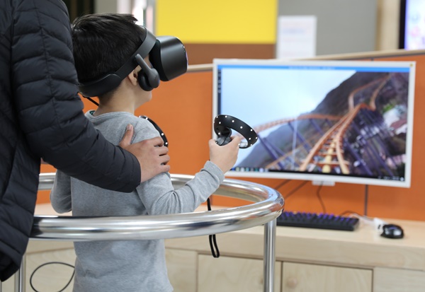 ▲ 게임문화체험관에서 한 학생이 직원의 도움을 받아 VR을 체험하고 있다.ⓒ충북도특수교육원