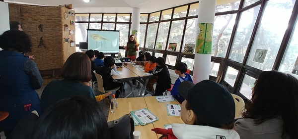▲ 충북 청주시가 23일 청주시 흥덕구 솔밭공원에서 ‘명상숲 코디네이터’와 함께하는 ‘양서류는 내 친구’특강을 운영해 초등학생 자녀를 동반한 가족들로부터 큰 호응을 얻었다.사진은 솔밭공원내 솔밭책방에서 파워포인트를 이용한 양서류 관련 설명 장면.ⓒ청주시