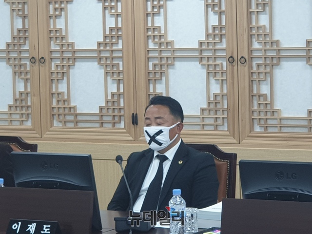 ▲ 9일 오후 도의회에서 열린 3차 추경 교육위 제안 설명회 자리에서 이재도 의원이 삭감처리된 교육청 예산이 다시 살아난 것에 대한 항의표시로 검은 넥타이에 x표시 마스크를 쓰고 항의하고 있다.ⓒ뉴데일리