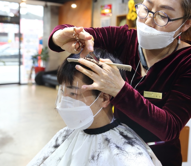 ▲ 12일 나래민스헤어 김보민 대표가 페이스 필림을 활용해 박수양(25 왜관읍)씨의 머리칼을 자르고 있다.ⓒ칠곡군