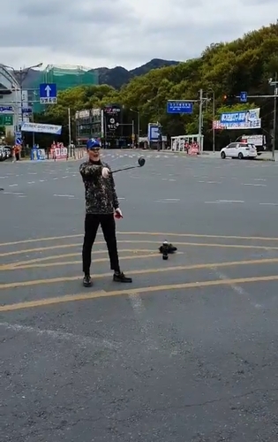 ▲ 한 남성이 홍준표 후보 유세차에 접근한 뒤 도로 안전지대에 콜라병을 세우고 후보를 향해 골프채를 휘두르며 욕설을 하고 있다.ⓒ홍 후보 측