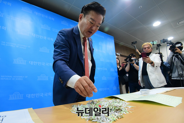 ▲ 21일 국회 기자회견에서 민경욱 의원이 경기도 우체국 인근에서 발견됐다고 주장하며, 파쇄된 투표용지와 우편봉투 조각을 기자들 앞에 펼치고 있다.ⓒ이종현 기자