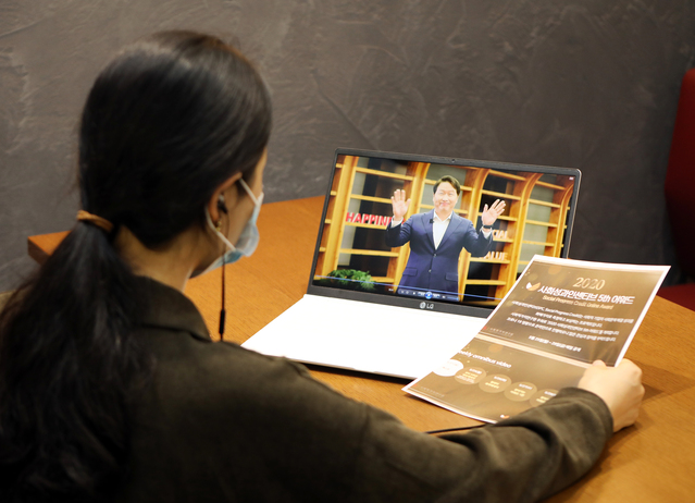 ▲ 최태원 SK회장(컴퓨터 화면 속)의 사회성과인센티브 어워드 개최 축하 인사를 행사 관계자가 시청하고 있다.ⓒSK