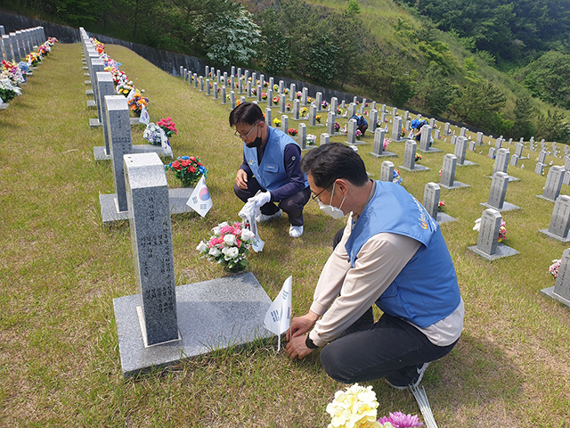 ▲ 포스코 글로벌품질서비스실 임직원들이 지난 30일 국립영천호국원에서 묘역을 정리하고 준비한 태극기를 꽂고 있다.ⓒ포스코
