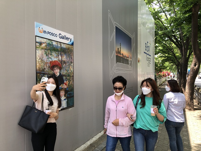 ▲ 시민들이 포스코건설이 시공중인 서울 신길3구역 현장 펜스에 설치된 'With POSCO 갤러리' 앞에서 사진을 찍으며 즐거워하고 있다.ⓒ포스코건설