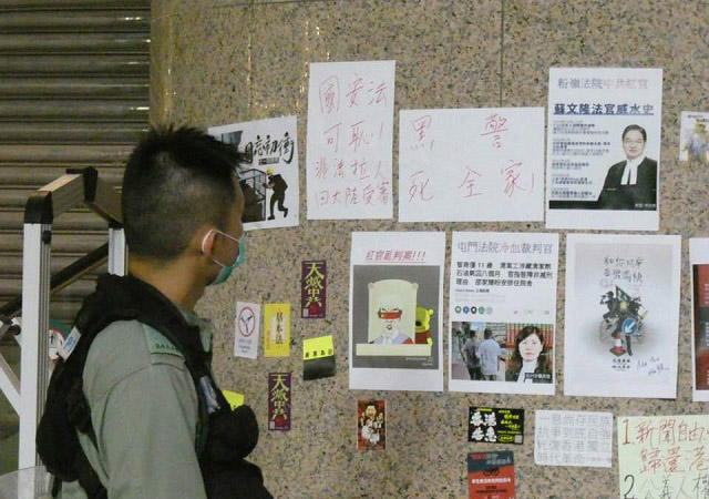 ▲ 코즈웨이베이 (銅鑼灣) 타임즈스퀘어에 나붙은 경찰 비난벽보 (黑警死全家)를 바라보는 경찰ⓒ허동혁