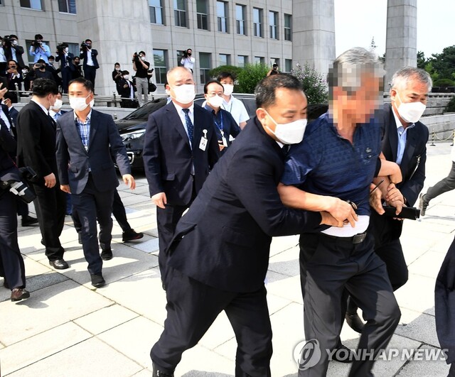 ▲ 국회의사당 앞에서 문재인 대통령을 향해 구두를 던진 시민을 연행하는 장면.ⓒ연합뉴스