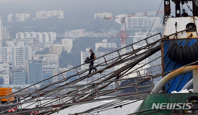 ▲ 29일 부산항에 정박 중인 러시아 선박에서 확진 선원들이 부산의료원으로 이송되기 위해 하선하고 있다. ⓒ뉴시스