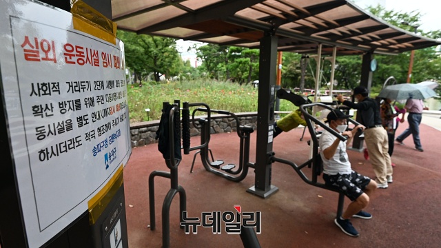 ▲ 지난 11일 오후 서울 송파구 석촌호수를 찾은 시민들이 실외 운동시설 임시폐쇄 안내문 옆에서 운동기구를 사용하고 있다. ⓒ권창회 기자