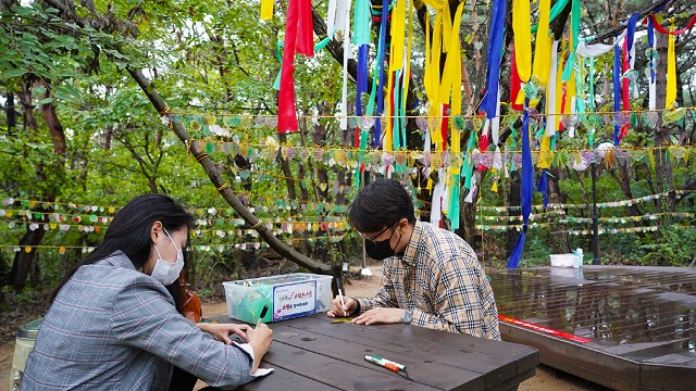 ▲ 경주엑스포공원 ‘사랑나무’에 걸 소망카드를 관광객들이 작성 하고 있다.ⓒ경주엑스포