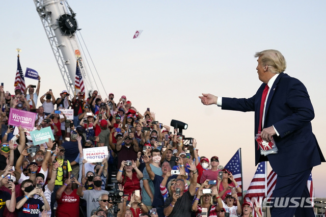 ▲ [샌퍼드=AP/뉴시스] 도널드 트럼프 미국 대통령이 지난 12일(현지시간) 미 플로리다주 샌퍼드의 올랜도 샌퍼드 국제공항에 선거 유세차 도착해 지지자들을 향해 마스크를 던져 주고 있다. 트럼프 대통령은 플로리다 유세 직전 코로나19 음성 판정을 받았다. ⓒ뉴시스